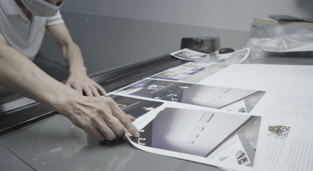 A printer examines unbound pages of the book Designing the Computational Image, Imagining Computational Design.